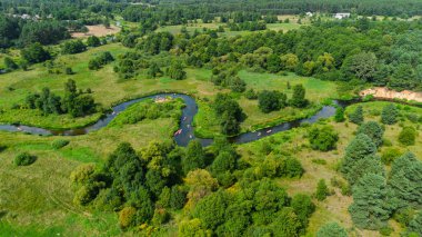 Bereketli yeşil çayırlar ve yaz doğa manzarasıyla çevrili Liswarta Nehri boyunca yüzen renkli kanoların hava aracı görüntüsü. Polonya 'da nehirde kayak yaparken. Nehirdeki kanolar.