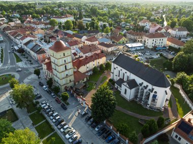 Polonya 'nın Lezajsk kentindeki ana meydanın hava aracı görüntüsü, güneşli bir yaz gününde çevresi yeşilliklerle çevrili tarihi binalar, kiliseler ve renkli mimariyle dolu..