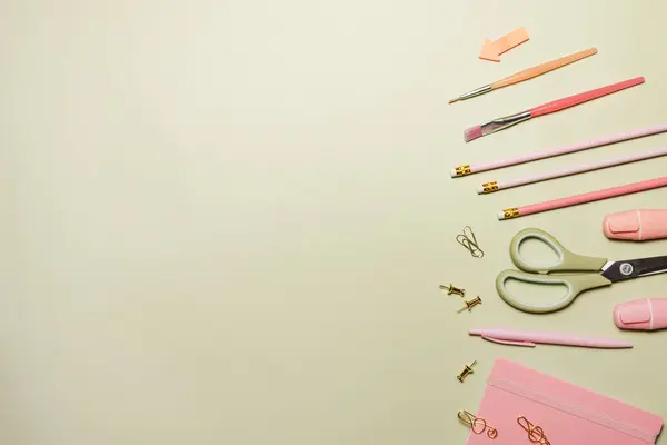 Yeşil arka planda pembe okul malzemeleri. Okula dönelim. Düz yerde, üst tarafta. Boşluğu kopyala.