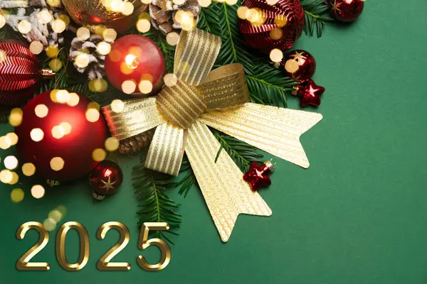 Altın fiyonklu yeşil Noel arkaplanı, Noel ağacı dalları ve Noel kırmızısı ve altın katmanlı. Tebrik kartı. Yeni yıl 2025 ve Noel. Uzayı kopyala Kutlama konsepti.