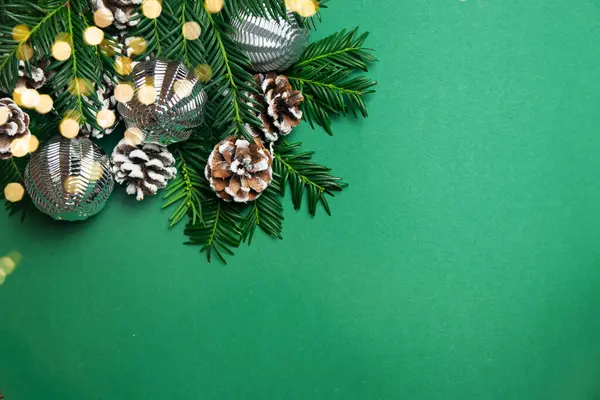 Noel ve Yeni Yıl konsepti. Köknar dallarının, çam kozalaklarının ve yeşil arka planda Bokeh ile gümüş Noel toplarının dekorasyonunun en üst görüntüsü. Boşluğu kopyala.