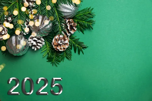 Noel ve 2025 yılbaşı konsepti. Canlı köknar dallarından, çam kozalaklarından ve yeşil arka planda gümüş Noel toplarından yapılan dekorasyonun en üst görüntüsü. Uzayı kopyala Festivalsel Arkaplan.