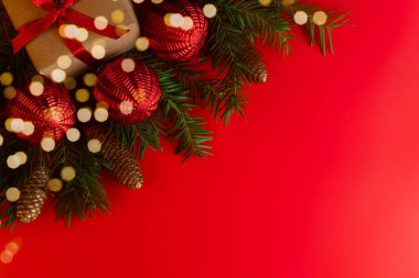 Noel ve Yeni Yıl konsepti. Kırmızı arka planda köknar dalları, çam kozalakları ve kırmızı Noel topları. Uzayı kopyala Şenlik arka planı. Tebrik kartı.