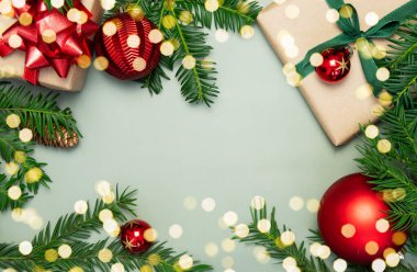 Ladin dalları, çam kozalakları, kırmızı toplar, yeşil arka planda kırmızı ve yeşil kurdeleli hediye kutuları. Noel günü ve yeni yıl konsepti. Şenlik havası. Boşluğu kopyala