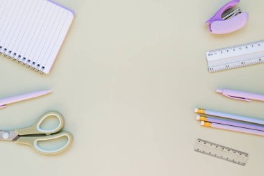 Yeşil arka planda kırtasiye malzemesi. Okula geri dönme zamanı. Not defteri, kalem, kalem, cetvel ve makas, zımba..