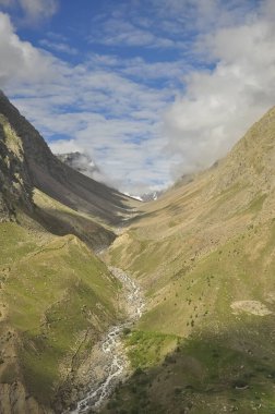 Tepeden tırnağa bulutlarla kaplı kuru dağlar, dağın tepesinden akan sular ve Manali-Leh otoyolunun bir bölümünde eriyen buzullardan eriyen karlar. 