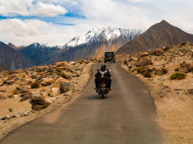 Ladakh, Hindistan - 26 Haziran 2022: Nubra Vadisi, Leh Ladakh, Jammu ve Kashmir, Hindistan 'da Diskit ve Khardung La Pass arasında güzel manzaranın tadını çıkaran bisikletçiler.