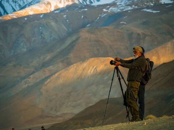 stock image Ladakh, India - June 23,2022: Unidentified photographer with tripod at Pangong lake with mountain range in background.