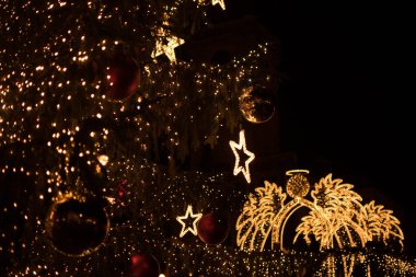 Arka planda aydınlanmış bir meleği ön planda süslenmiş bir süs dalıyla gösteren güzel bir görüntü. Karanlık bir zemindeki bu şenlik sahnesi Noel tebrik kartı için idealdir. Sıcak ve kişisel bir mesaj için boşluk bırakır..