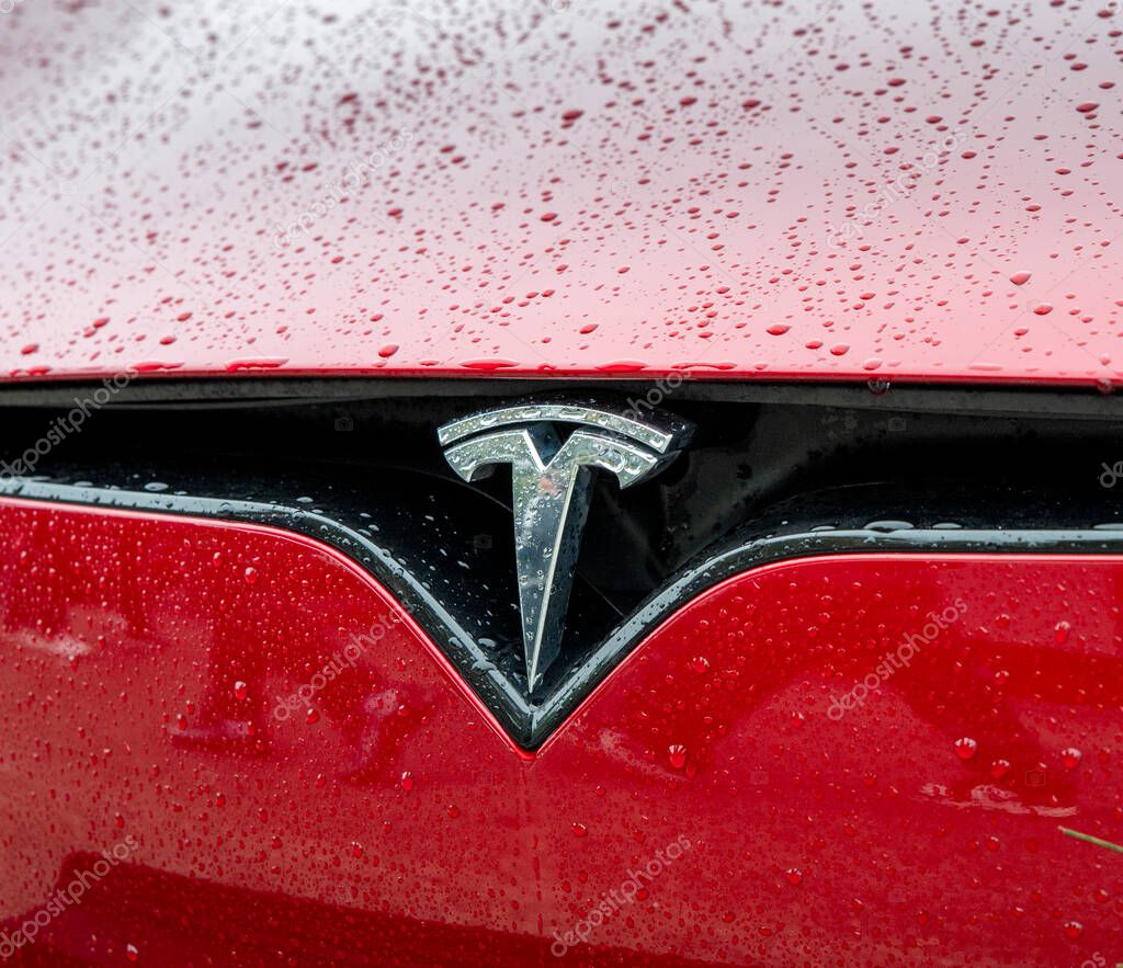 Nitra, Slovakia - October , 4, 2024 : Tesla brand on a car hood with water drops. A modern Tesla car close up. Tesla logo detail.