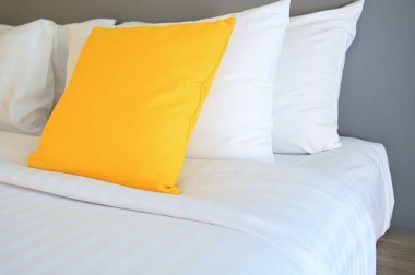 Beyaz yatakta sarı yastık, iç tasarım.