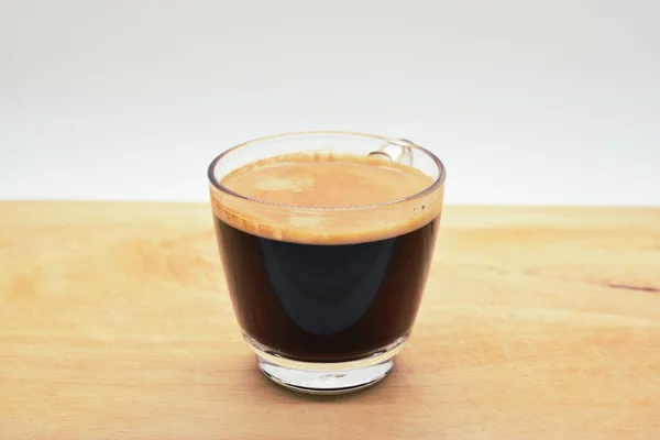 glass of hot black coffee put on wood background