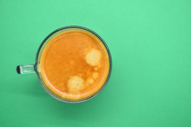 Yeşil arka planda bir bardak sıcak koyu kahve.