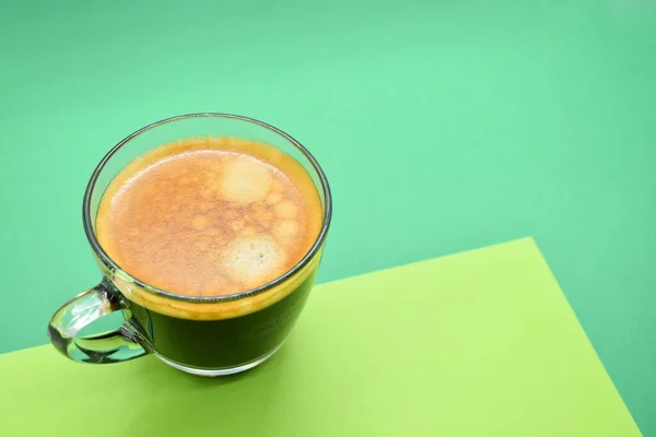 glass of hot black coffee put on green background