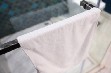 Banyodaki çelik askıda asılı beyaz yumuşak havlu.