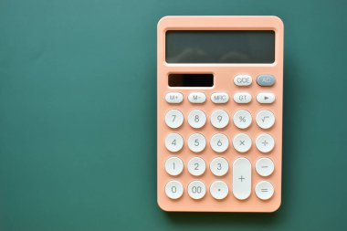modern şeftali rengi hesap makinesi ve yeşil arka planda beyaz düğme, iş ve finans muhasebe kavramı