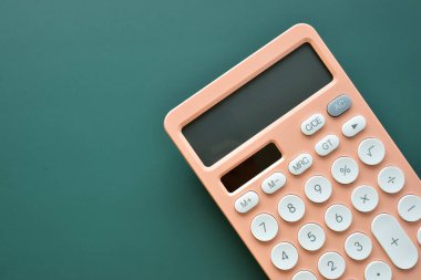 modern şeftali rengi hesap makinesi ve yeşil arka planda beyaz düğme, iş ve finans muhasebe kavramı