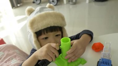 Küçük çocuk plastik hamuru ve inşaat setini oynayan şapka takıyor, yavaş çekim sahnesi.
