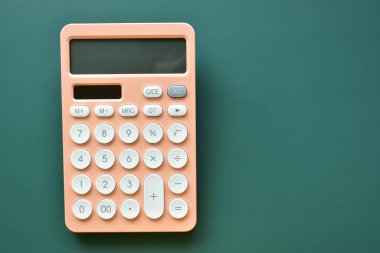 modern şeftali rengi hesap makinesi ve yeşil arka planda beyaz düğme, iş ve finans muhasebe kavramı