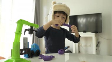Küçük çocuk plastik hamuru ve inşaat setini oynayan şapka takıyor, yavaş çekim sahnesi.
