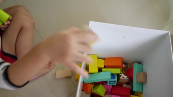 多くのカラフルな木製のブロック デザインのための創造的なおもちゃから街を構築する小さな男の子 — ストック動画