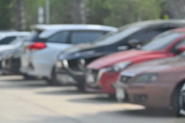 绿色树木的大型沥青停车场中的汽车 交通模糊图像 — 图库照片