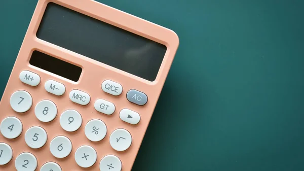 stock image modern peach colour pastel calculator and white button on green background, business and finance accounting concept