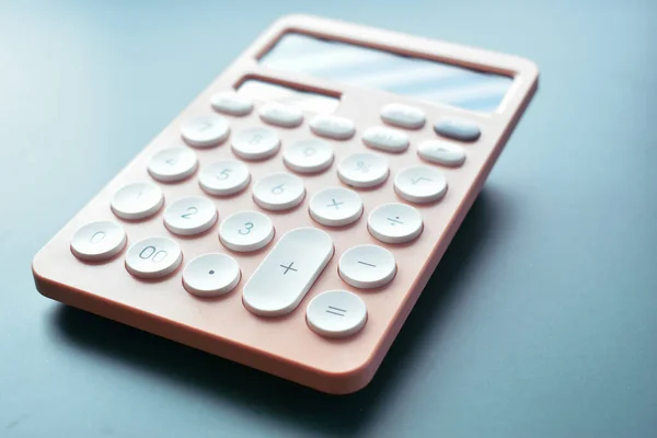 stock image close up modern peach colour pastel calculator and white button on blue background, business and finance accounting concept