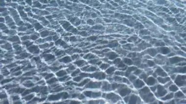 Yüzme havuzundaki şeffaf mavi suyun yüzeyindeki dalgalanma, 4K hareket sahnesini kapatır.