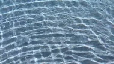 Yüzme havuzundaki şeffaf mavi suyun yüzeyindeki dalgalanma, 4K hareket sahnesini kapatır.