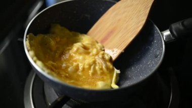 Çırpılmış yumurta, omlet, siyah tavayla kahvaltı hazırlama, yavaşça kızarmış yumurta sahnesi.