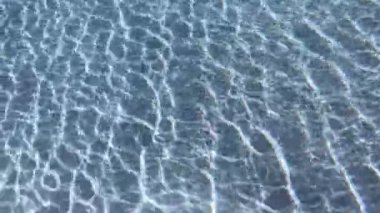 Yüzme havuzundaki şeffaf mavi suyun yüzeyindeki dalgalanma, 4K hareket sahnesini kapatır.