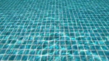 Yüzme havuzunda şeffaf mavi suyun altına dalmak, 4K hareket sahnesini kapatmak.