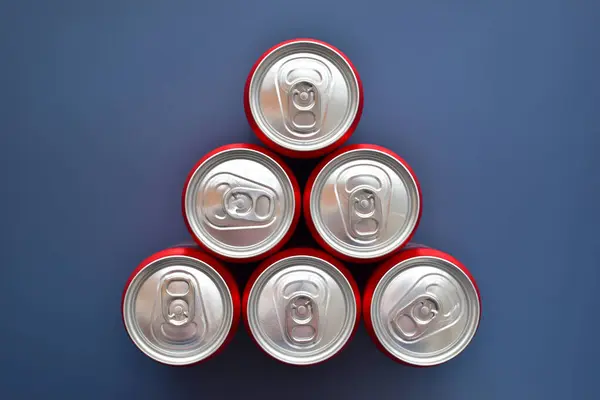 青い質の背景に置かれたアルミニウム赤い缶の柔らかい飲み物のグループを閉めて下さい ロイヤリティフリーのストック写真