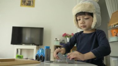 Küçük çocuk plastik hamuru ve inşaat setini oynayan şapka takıyor, yavaş çekim sahnesi.