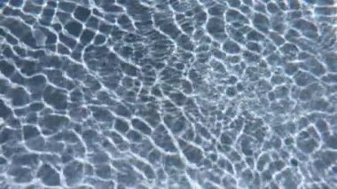Yüzme havuzunun su dalgaları, güneşin ışınları yavaş çekim sahnesinden geçiyor