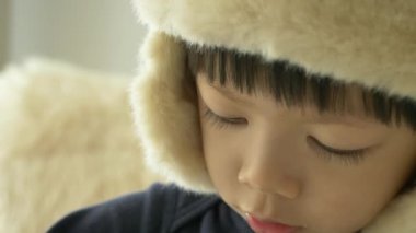 Mutlu küçük çocuk şapka takıyor ve evde gülümsüyor, yavaş çekim sahnesi.