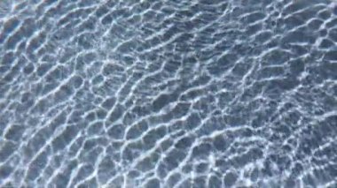 Yüzme havuzunun su dalgaları, güneşin ışınları yavaş çekim sahnesinden geçiyor