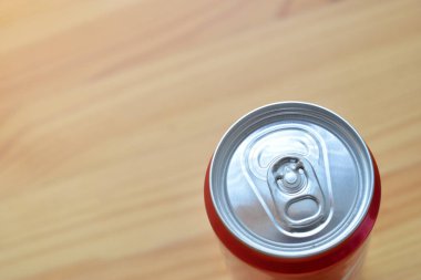 Alüminyum kırmızı meşrubat kutuları kahverengi ahşap masaya konur.