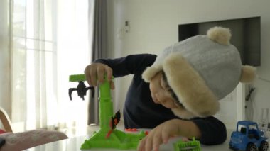 Küçük çocuk plastik hamuru ve inşaat setini oynayan şapka takıyor, yavaş çekim sahnesi.