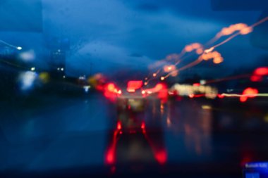 Gecenin karanlığında arabanın ışığı, yağmurlu bir günde arka planda bulanıklık