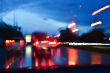 Gecenin karanlığında arabanın ışığı, yağmurlu bir günde arka planda bulanıklık