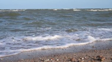 Mavi gökyüzü ve güzel doğal arkaplan ile deniz ve kum üzerinde yavaş çekim su dalgası