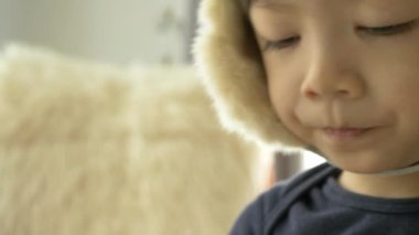 Mutlu küçük çocuk şapka takıyor ve evde gülümsüyor, yavaş çekim sahnesi.