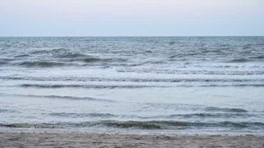 Mavi gökyüzü ve güzel doğal arkaplan ile deniz ve kum üzerinde yavaş çekim su dalgası