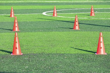 Yapay yeşil çimen futbol sahası ve turuncu eğitim konileri