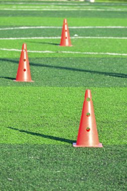 Yapay yeşil çimen futbol sahası ve turuncu eğitim konileri