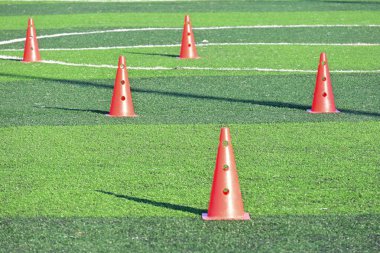 Yapay yeşil çimen futbol sahası ve turuncu eğitim konileri