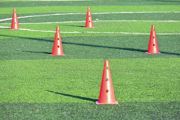 Yapay yeşil çimen futbol sahası ve turuncu eğitim konileri