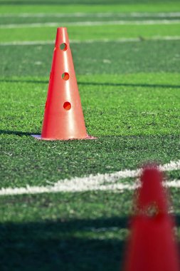 Yapay yeşil çimen futbol sahası ve turuncu eğitim konileri